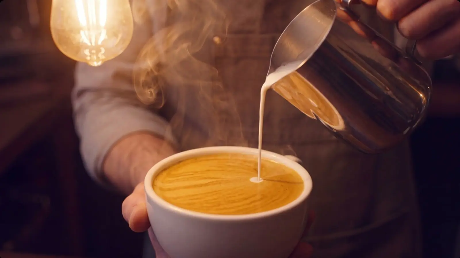 Beispielszene Rösterei am Morgen: Milch fließt in einen Espresso, darüber eine warme Lampe